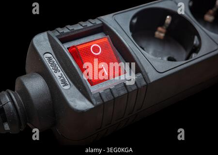 The electrical outlet strip shows a power switch that is turned on. The red light is illuminated, indicating that power is flowing to the outlets. Thi Stock Photo