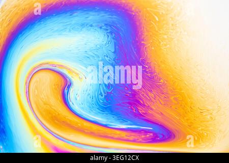 Close-up macro view of iridescent colors and textures on a soap bubble film, showcasing fluid dynamics and light interference Stock Photo
