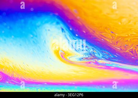 Close-up view of soap bubble iridescence showcasing a dynamic interplay of blues, yellows, and purples in swirling patterns Stock Photo