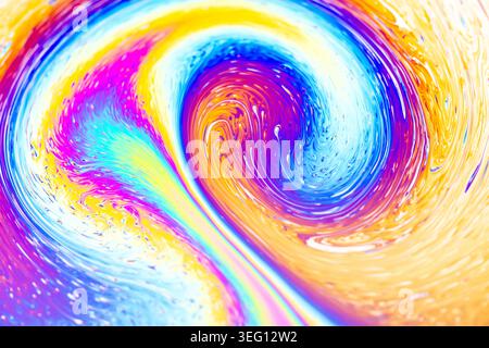 Close-up view of iridescent colors swirling and blending on a soap bubble's surface, showcasing a dynamic, fluid abstract design Stock Photo