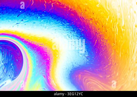 Macro view of a soap bubble film displaying vibrant, swirling patterns of blue, purple, yellow, and orange hues Stock Photo
