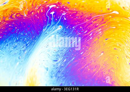 Abstract macro view of iridescent soap film displaying a spectrum of bright colors and fluid patterns, creating a dynamic visual effect Stock Photo