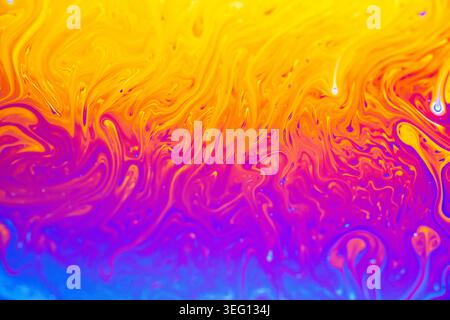 Abstract macro photography captures the iridescent, swirling patterns of a soap bubble's surface, displaying a spectrum of vivid colors Stock Photo