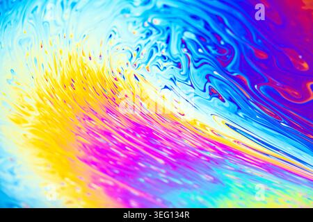 Close-up view of iridescent soap film showing interference patterns of bright colors like yellow, pink, and blue Stock Photo