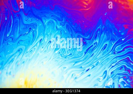 Close-up view of iridescent colors and flowing patterns on a soap bubble surface, creating a mesmerizing abstract background Stock Photo