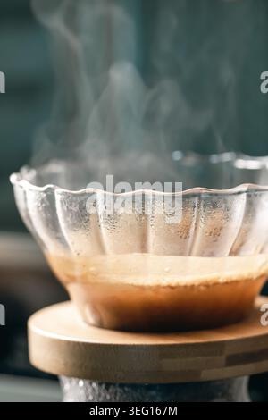 Freshly ground coffee brewing process pouring through glass cone dripper close up view Stock Photo