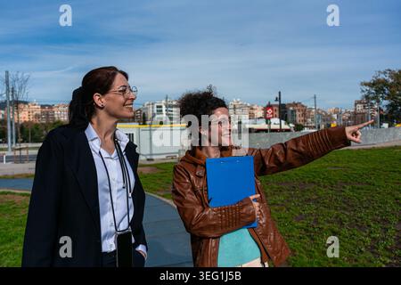Businesswomen pointing looking ahead discussing project outdoors Stock Photo