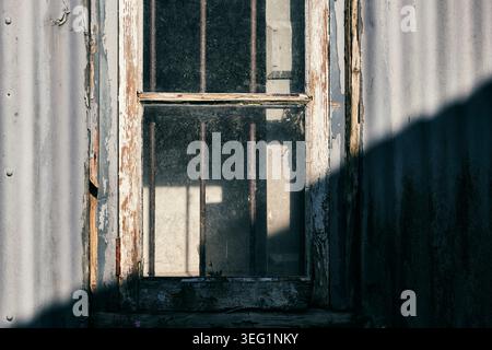 A rotten wooden window frame half cast in shadow. Stock Photo