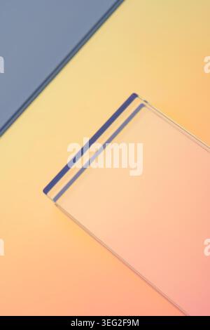 Minimal abstract scene with a translucent glass rectangle on a soft neon pastel gradient background, clean geometric lines, warm light. Stock Photo