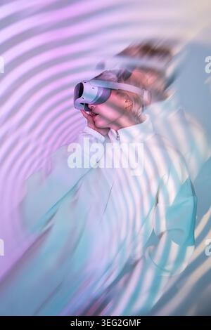 Futuristic woman wearing a VR headset in soft neon lighting, surrounded by abstract ripple reflections. Minimal portrait with dreamy motion blur, tech Stock Photo