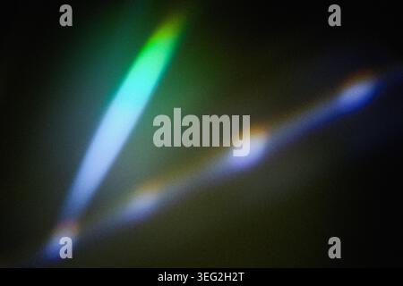 Light leaks creating lens flare and abstract rainbow effect on dark background Stock Photo