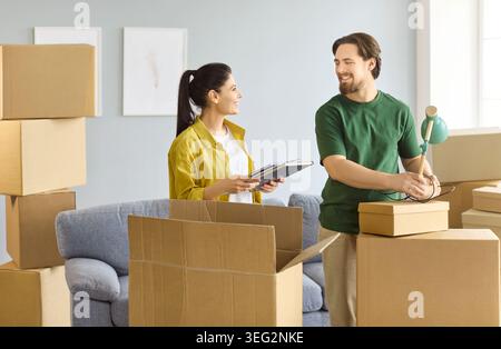 Smiling couple unpacking boxes and planning setup in their bright new apartment Stock Photo