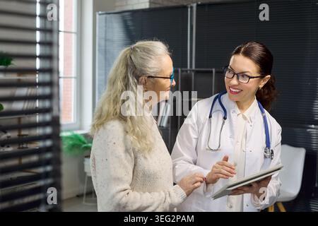 Smiling doctor discussing test results with senior patient using tablet computer Stock Photo