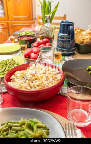 Easter dinner table arranged with red eggs and boeuf salad in the foreground Stock Photo
