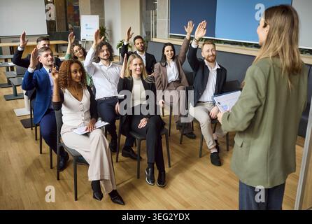 Business team workshop with coach as employees raise hands during office training Stock Photo