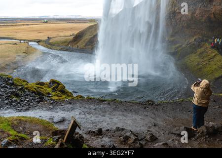 Tourists in the cave of Seljalandsfoss, a wonderful waterfall located in the South Region in Iceland right by Route 1 Stock Photo