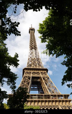 Eiffel Tower seen through trees from below the tower on the Champ de Mars side in Paris, France. Stock Photo