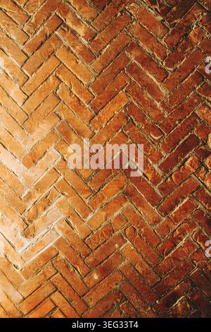 Worn terracotta brick floor laid in a herringbone pattern with visible grout lines, scratches and warm red-brown tones for backgrounds, architecture, Stock Photo