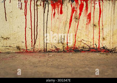 Red paint drips and splatter streak down a weathered, textured wall above a rough concrete ground, evoking urban decay, grit and raw abstract street-a Stock Photo