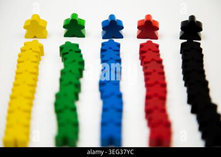 Side view of rows of wooden multi-colored men, with a large man at the base, divided into teams on a Stock Photo