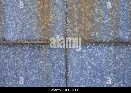 Four galvanized old steel sheets with rust spots and aged rivets. Industrial background and metallic texture with signs of corrosion. Vintage architec Stock Photo