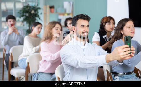 Students using mobile phones to scan QR code during interactive lesson Stock Photo