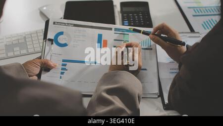 Two young Asian businesswomen discuss investment project working and ...