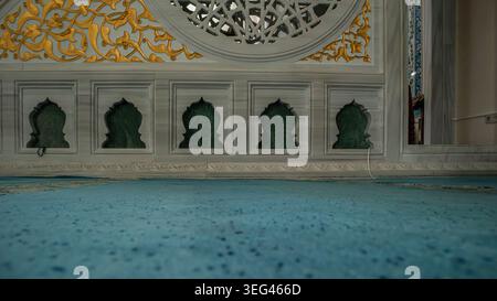 ISTANBUL, Türkiye - April 30, 2026.Green marble niches are set into a white stone wall over a soft turquoise prayer carpet. Stock Photo