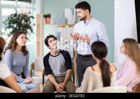 Male teacher talking to interested students sitting in a circle Stock Photo
