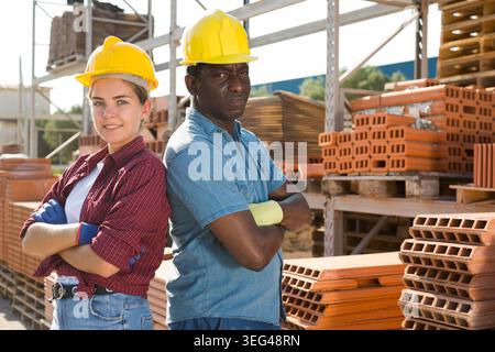 Workers in hardhats standing in construction material storage Stock Photo