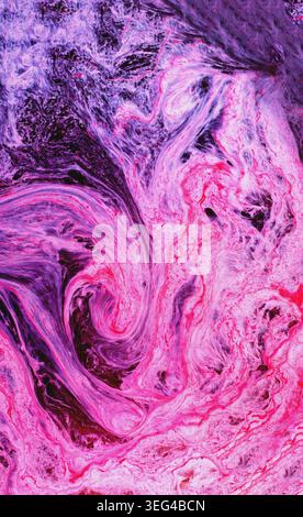 Vibrant pink and purple liquids blending, creating dynamic swirls and marbling patterns. Abstract flowing shapes forming a fluid background Stock Photo