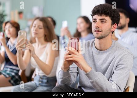 Young guy using mobile phone to scan QR code during interactive lesson Stock Photo