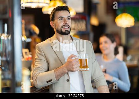 Young man drinks beer and watches match at bar Stock Photo