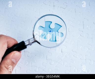 Data protection concept with magnifying glass focusing on missing puzzle piece and lock icon. Cybersecurity analysis, problem solving, security invest Stock Photo