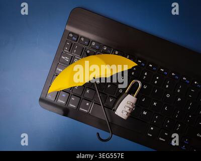 A small yellow umbrella and a combination padlock sit on a black computer keyboard over a blue surface. Stock Photo