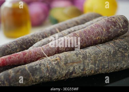 black carrots on table with various fruits and oil Stock Photo