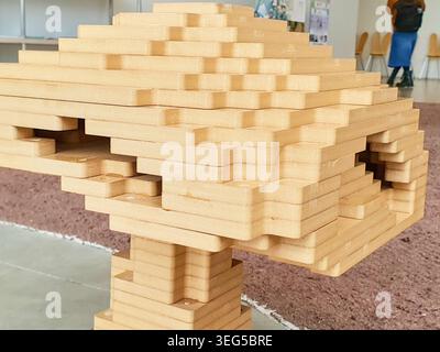 A detailed architectural structure constructed from light-colored wooden rectangular blocks, stacked in a tiered formation with multiple overhangs Stock Photo