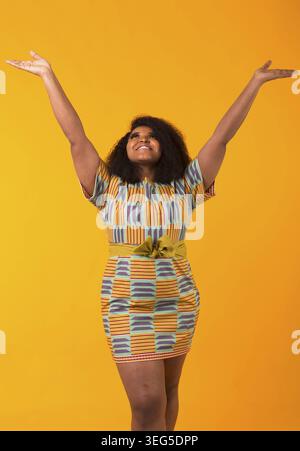 Happy beautiful african american girl with an afro hairstyle. Portrait on yellow background. Girl looking up Stock Photo