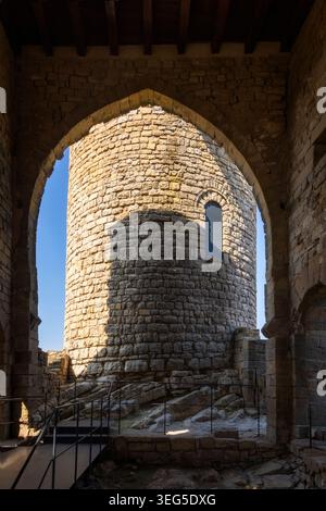A striking view of a robust cylindrical tower within the historic stone structure of Boixadors Castle in Anoia, Catalonia, framed by an arch and featu Stock Photo