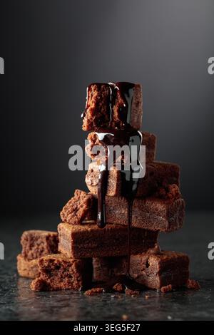 Brownie pieces on a black background. Melted chocolate drips down the brownie. Stock Photo