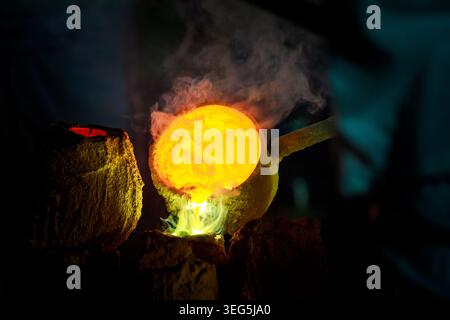 A closeup of molten alloy being poured into a casting mold illustrating a highheat industrial metal manufacturing process in a dark foundry. Stock Photo