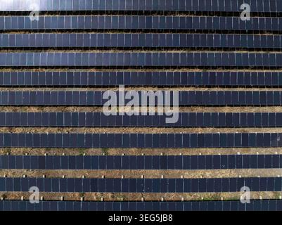A highangle view of an industrial solar farm with repeating rows of photovoltaic panels in a landscape symbolizing green energy infrastructure. Stock Photo
