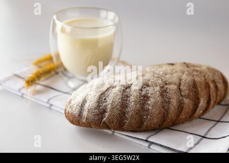Fresh rustic bread loaf with glass of milk on kitchen towel Stock Photo