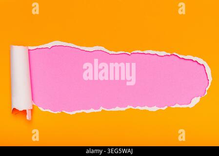A piece of vivid orange paper torn open to reveal a bright pink surface underneath. Stock Photo