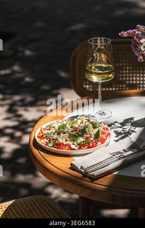 Mediterranean salad with wine on sunny table Stock Photo