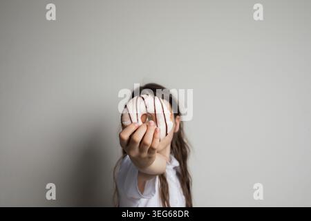 White glazed donut with chocolate lines in hand. Tasty doughnuts, sweet dessert food Stock Photo