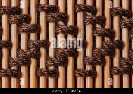 Detailed macro shot showcasing the intricate weaving of natural bamboo reeds bound together by coarse brown twine, forming a rustic and organic textur Stock Photo
