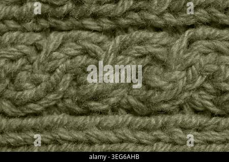 Detailed view of a thick, woolen textile featuring a cable knit pattern with visible yarn strands and a soft, fuzzy texture Stock Photo