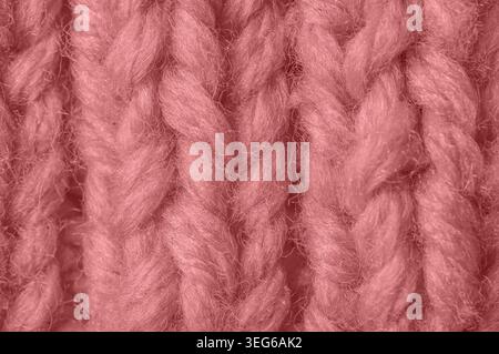 Detailed texture of chunky, soft pink yarn with visible fibers and a braided knit stitch creating depth and dimension Stock Photo