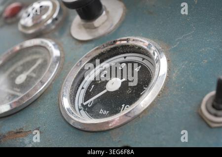 Vintage blue industrial control panel with analog pressure gauges, switches and worn metal surface Stock Photo